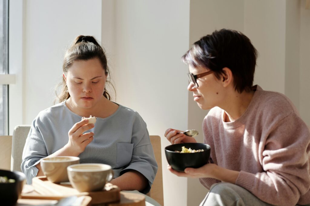 pexels-photo-4058053-4058053 Two women sharing breakfast, one with Down syndrome, fostering togetherness and care.